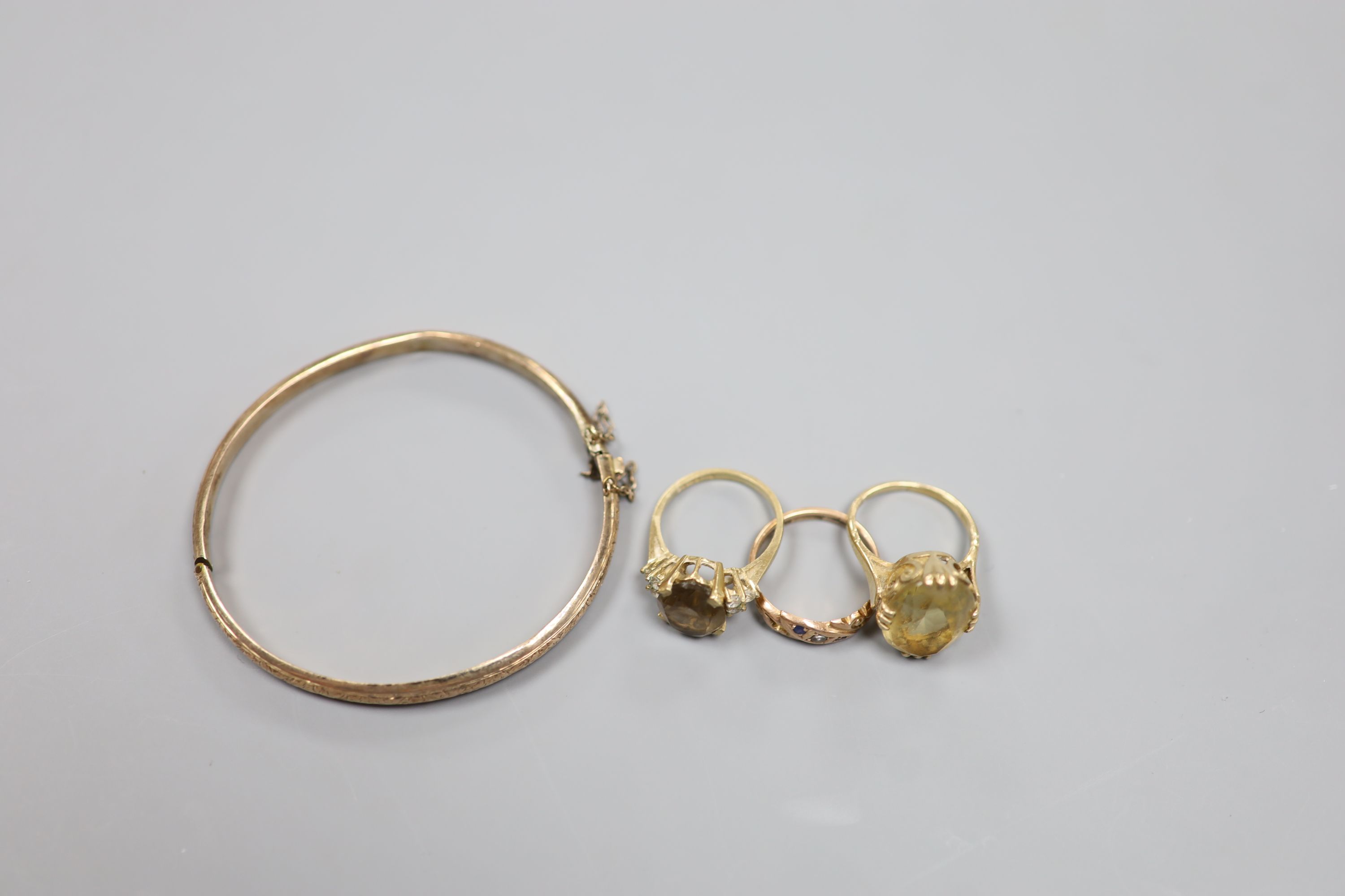 Three assorted 9ct and gem set rings and a 9ct gold hinged bangle